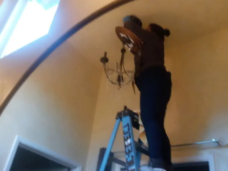 Electrician installing a chandelier in a South Ogden residence